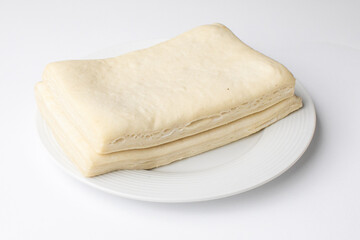 Folded unleavened dough on white plate, commonly used for Passover baking and kosher meal preparations