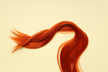 Red hair strand on beige background