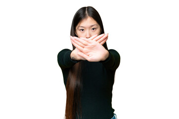 Young Asian woman over isolated chroma key background making stop gesture with her hand to stop an...