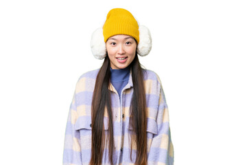 Young Asian woman wearing winter muffs over isolated chroma key background with surprise facial...