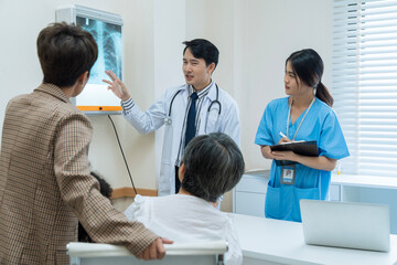 Doctors and patient talking about therapy. Asian doctor and patient looking at x ray film together.
