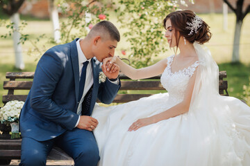 A man and a woman are sitting on a bench, the man is kissing the woman's hand