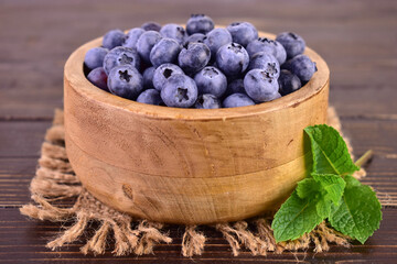 Blueberries in a wooden bowl on a dark wooden background.Close-up.
