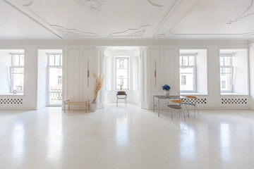 bright interior design of spacious living room with white walls and decorative unique historical moldings on ceiling stylish modern furniture in warm colors without people daylight through the windows