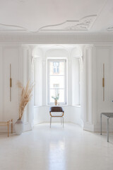 bright interior design of spacious living room with white walls and decorative unique historical moldings on ceiling stylish modern furniture in warm colors without people daylight through the windows