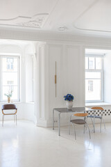 bright interior design of spacious living room with white walls and decorative unique historical moldings on ceiling stylish modern furniture in warm colors without people daylight through the windows