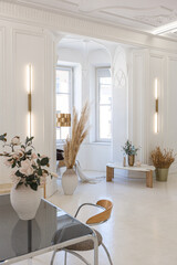 bright interior design of spacious living room with white walls and decorative unique historical moldings on ceiling stylish modern furniture in warm colors without people daylight through the windows