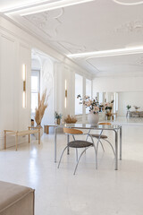 bright interior design of spacious living room with white walls and decorative unique historical moldings on ceiling stylish modern furniture in warm colors without people daylight through the windows