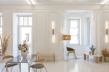 bright interior design of spacious living room with white walls and decorative unique historical moldings on ceiling stylish modern furniture in warm colors without people daylight through the windows