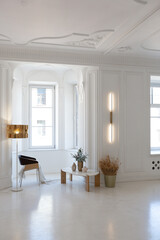 bright interior design of spacious living room with white walls and decorative unique historical moldings on ceiling stylish modern furniture in warm colors without people daylight through the windows