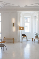 bright interior design of spacious living room with white walls and decorative unique historical moldings on ceiling stylish modern furniture in warm colors without people daylight through the windows