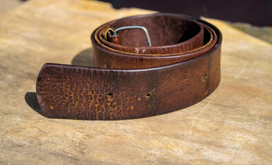 Part of a leather brown belt with a metal buckle