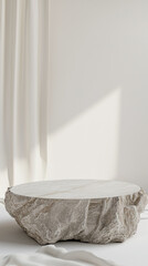 Natural rock with a smooth top in a minimalist set up with sunlight streaming through a white curtain, casting a soft shadow on the wall.
