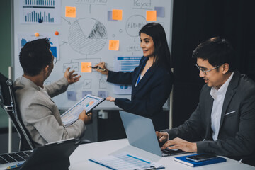 Group of confident business people point to graphs and charts to analyze market data, balance sheet, account, net profit to plan new sales strategies to increase production capacity.