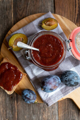 Traditional german plum butter in a jar on wooden table background