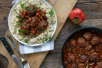 Meatballs in a delicious spicy sauce. Served with brown rice. Homemade food on rustic and wooden...