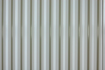 Obraz premium Metal wall made of profiled iron ladder. Surface covered with grey paint. There are glares from lighting. Background. Texture.