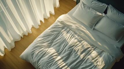A serene bedroom features a beautifully made bed with a crisp white comforter and matching pillows. Natural light filters through sheer curtains, creating a calm atmosphere