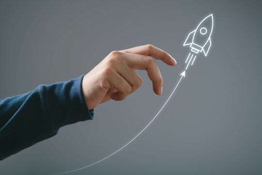 Hand guiding drawn rocket upward, symbolizing innovation, success, and growth in a minimalistic and futuristic concept.
