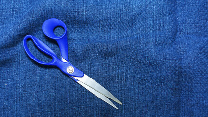 Large tailor's scissors lie on blue fabric