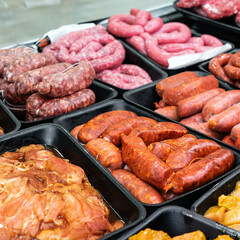 raw meat for sale in a butcher shop. There is spicy chorizo, sweet chorizo, sausages, red meat and spicy chicken