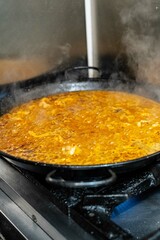cooking typical Spanish paella with fire, made with rice, seafood, pepper, saffron.