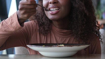 Beautiful African American woman eating pasta with seafood in a restaurant. Woman enjoying food....