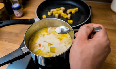 Chef at the kitchen preparing pumpkin porridge with tofu and vegetables
