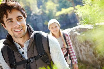 Fototapeta premium Mountain, trekking or happy couple hiking in woods for love or romantic outdoor adventure in nature. Journey, hikers or people in forest together on holiday vacation, trip or break to explore park
