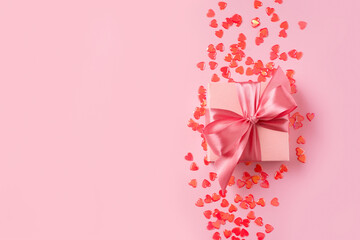 Pink gift box with bow and red heart confetti
