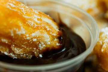 churros covered with sugar sprinkles with chocolate dipping on a box