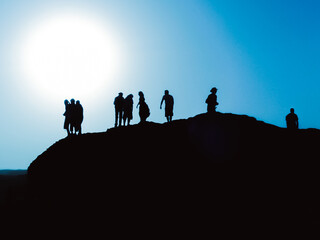 Silhouette with colors of white, blue, and black of group of people against the Sun standing over a hill in the White Desert of Egypt