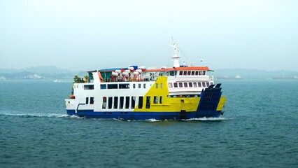 photo of a ferry carrying vehicles and passengers in Indonesia on a rainy morning