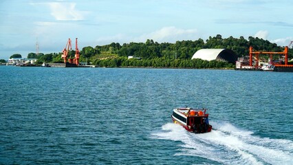 Fototapeta premium photo of a small fast ferry sailing towards the destination port, photo taken from behind