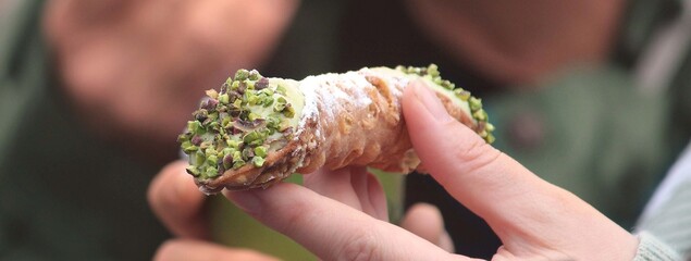 Pistachio Cannoli being held by a woman