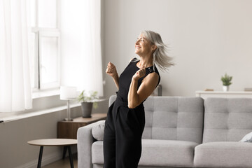 Carefree mature blonde woman in casual clothes spend pastime at home listening favourite track...