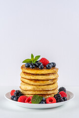 Delicious pancakes with fresh berries on white table. Food concept.