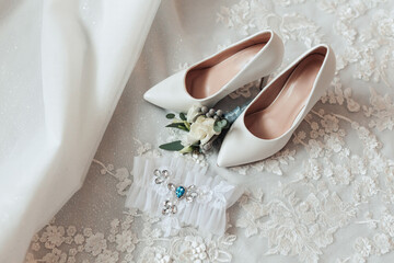 A pair of white shoes with a flower on them and a ring on the left foot