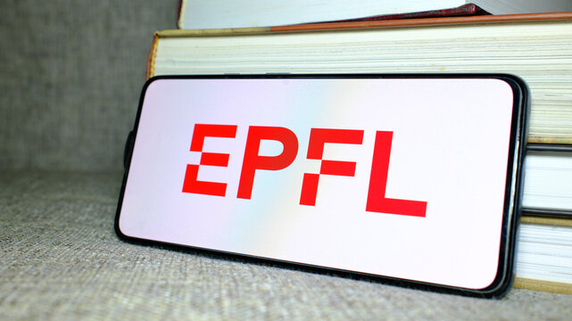 &Eacute;cole polytechnique f&eacute;d&eacute;rale de Lausanne (EPFL) logo on phone screen with stack of books behind. London, UK, 08.25.2024