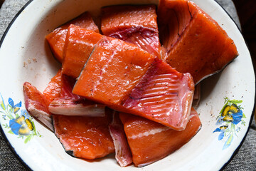 Pieces of raw salmon on the plate sprinkled with pepper and salt ready for cooking