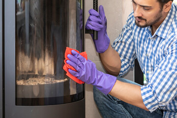 A young man cleans a fireplace to be prepared for the harsh winter during an energy crisis	