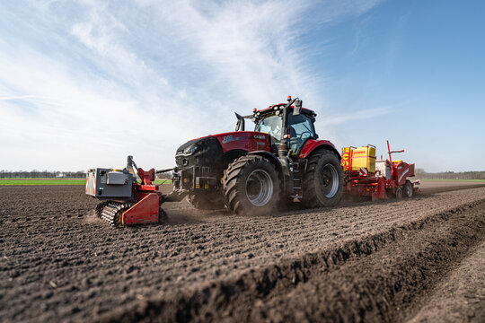 Kartoffelanbau - moderner Case-IH Traktor beim Legen von Kartoffeln mit einer Grimme Kartoffel-Legemaschine.
