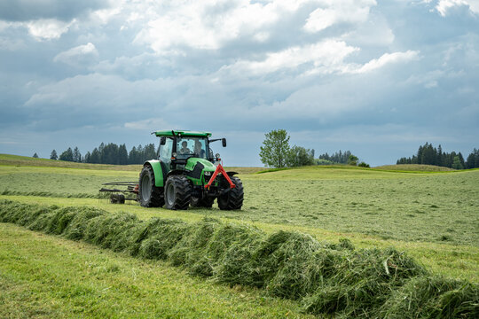 Traktor der Firma Deutz mit angeh&auml;ngten Schwader beim Heu wenden.