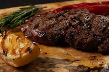Closeup grilled Rib Eye Black Angus served with pepper and herbs on wooden background.