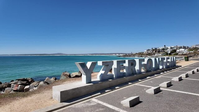 Yzerfontein Western Cape South Africa. 27.03.2024. Video. Yzerfontein town sign located in a coastal car park area with background of homes and the sea.