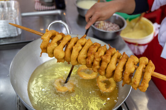 A woman is cooking picarones in a pan