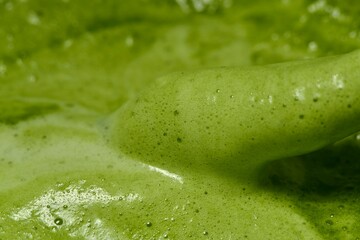 A close-up image of green tea with a smooth, frothy texture. The vibrant green color and visible air bubbles on the surface highlight the freshness and quality of Softness of the tea foam