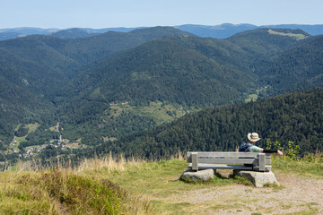 Naklejka premium randonneur assis sur un banc au sommet du Ballon d'Alsace dans les Vosges en train d'admirer les paysages de forêts vosgiennes