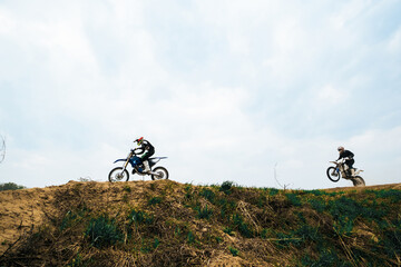 Motorcyclist jumping and riding on rear wheel at enduro motocross training ground