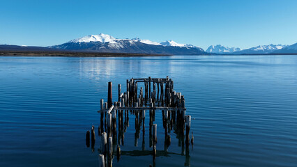 Famous Pier At Puerto Natales In Magallanes Chile. Snowy Mountains. Lake Landscape. Magallanes Chile. Water Background. Famous Pier At Puerto Natales In Magallanes Chile.